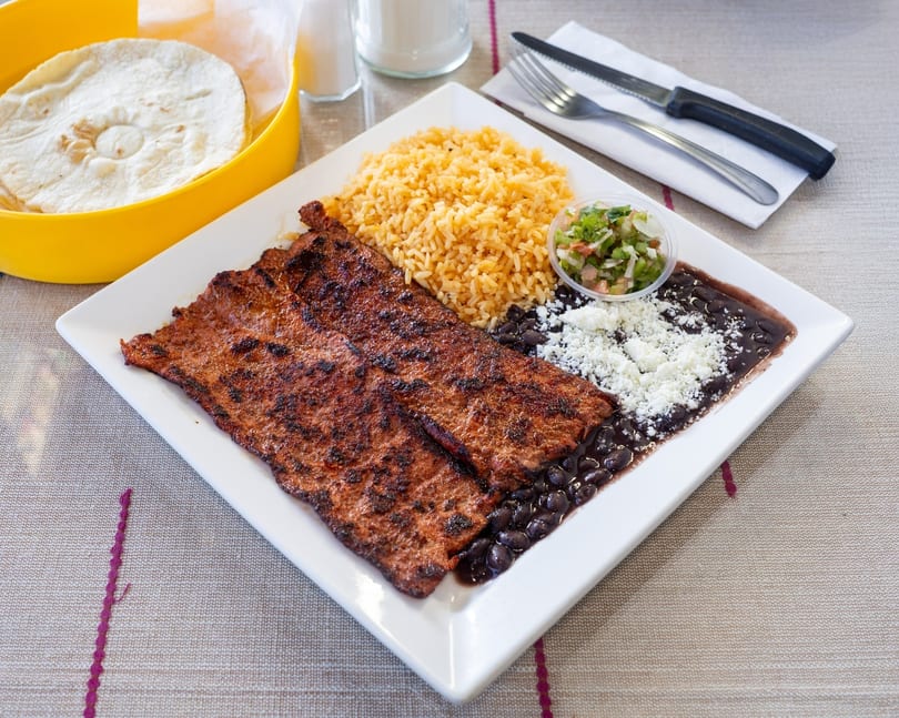 Grilled steak with rice, black beans, crumbled cheese, pico de gallo, and tortillas.