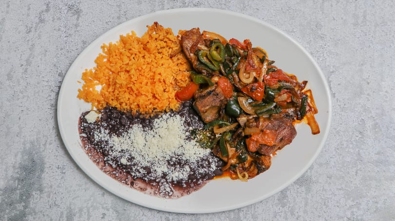 Pork ribs with peppers, onions, tomatoes, rice, and refried beans with cheese.