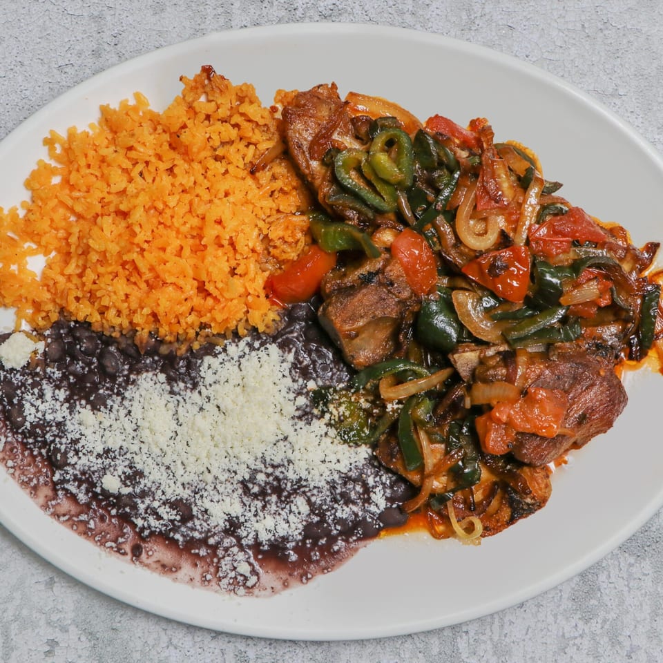 A plate of Mexican food with orange rice, black beans with cheese, and meat with peppers and tomatoes.